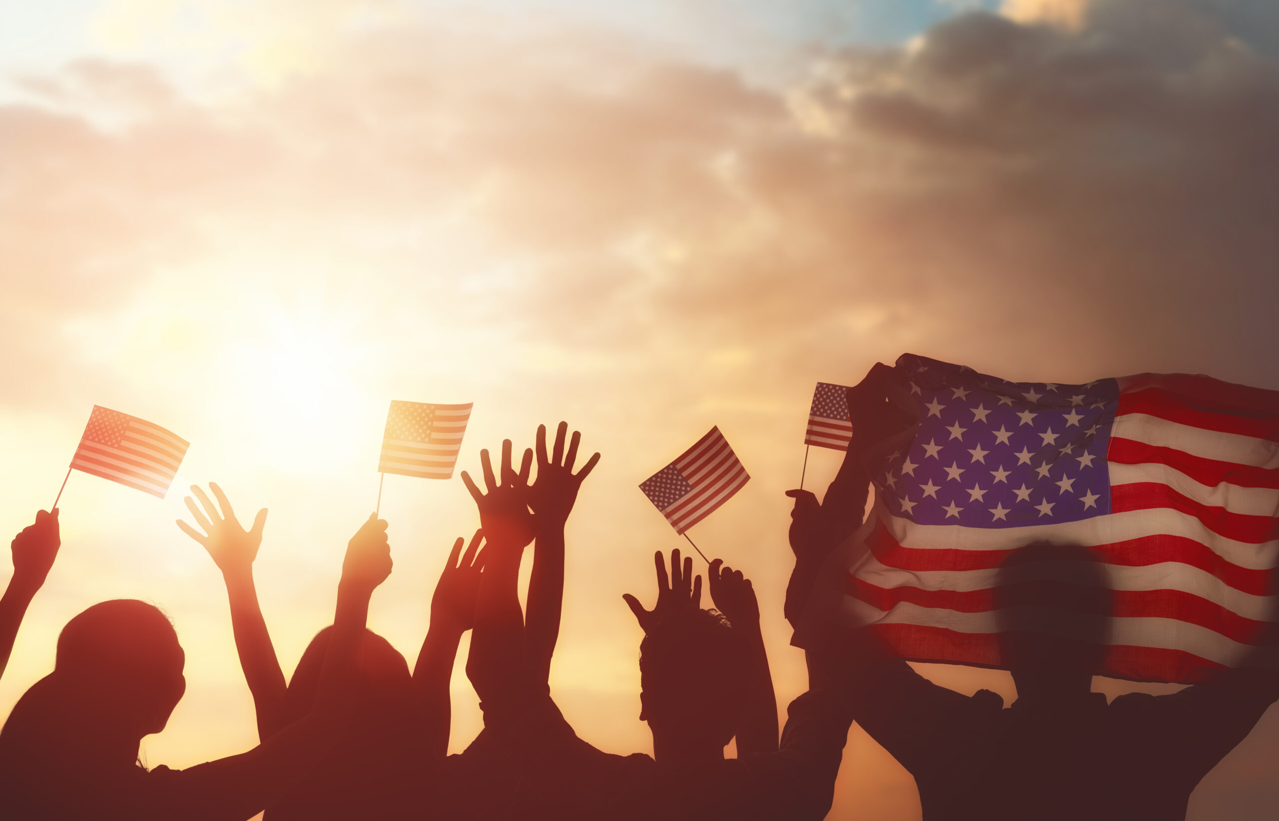 Americans waving flags and hands at sunrise